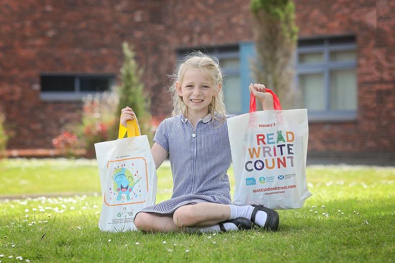 Penny from Moffat Academy holding up her winning design on the back of the P2 and P3 Read, Write, Count bags